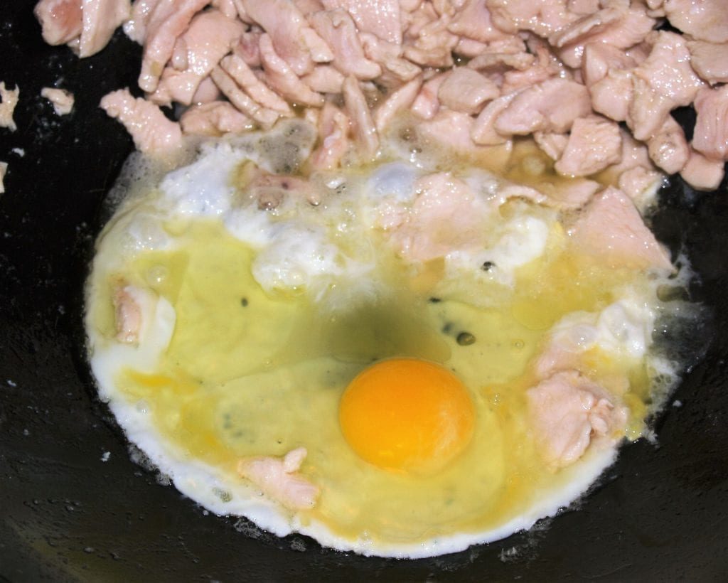 Pollo y huevos en rodajas en un wok